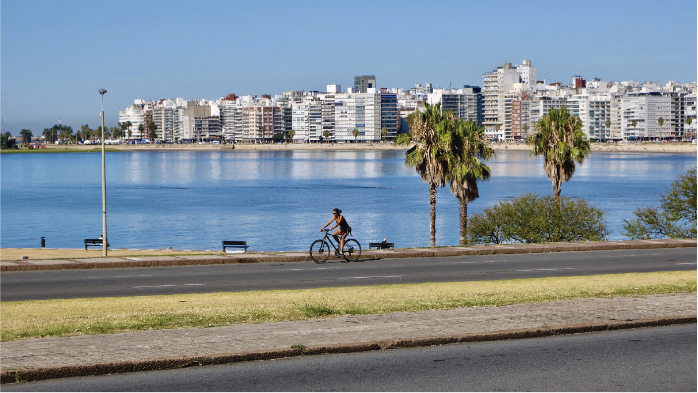 Mujer andando en bicicleta en una rambla de Montevideo